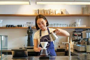 Barista making pour-over coffee with a white kettle at a cafe in Ekkamai, Bangkok